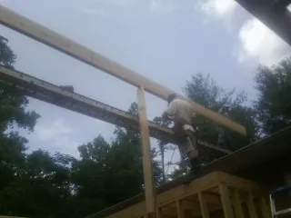 Carpenter setting a ridge beam over a new addition frame — Ice Dam Removal by Roofing Brothers in Kennedy