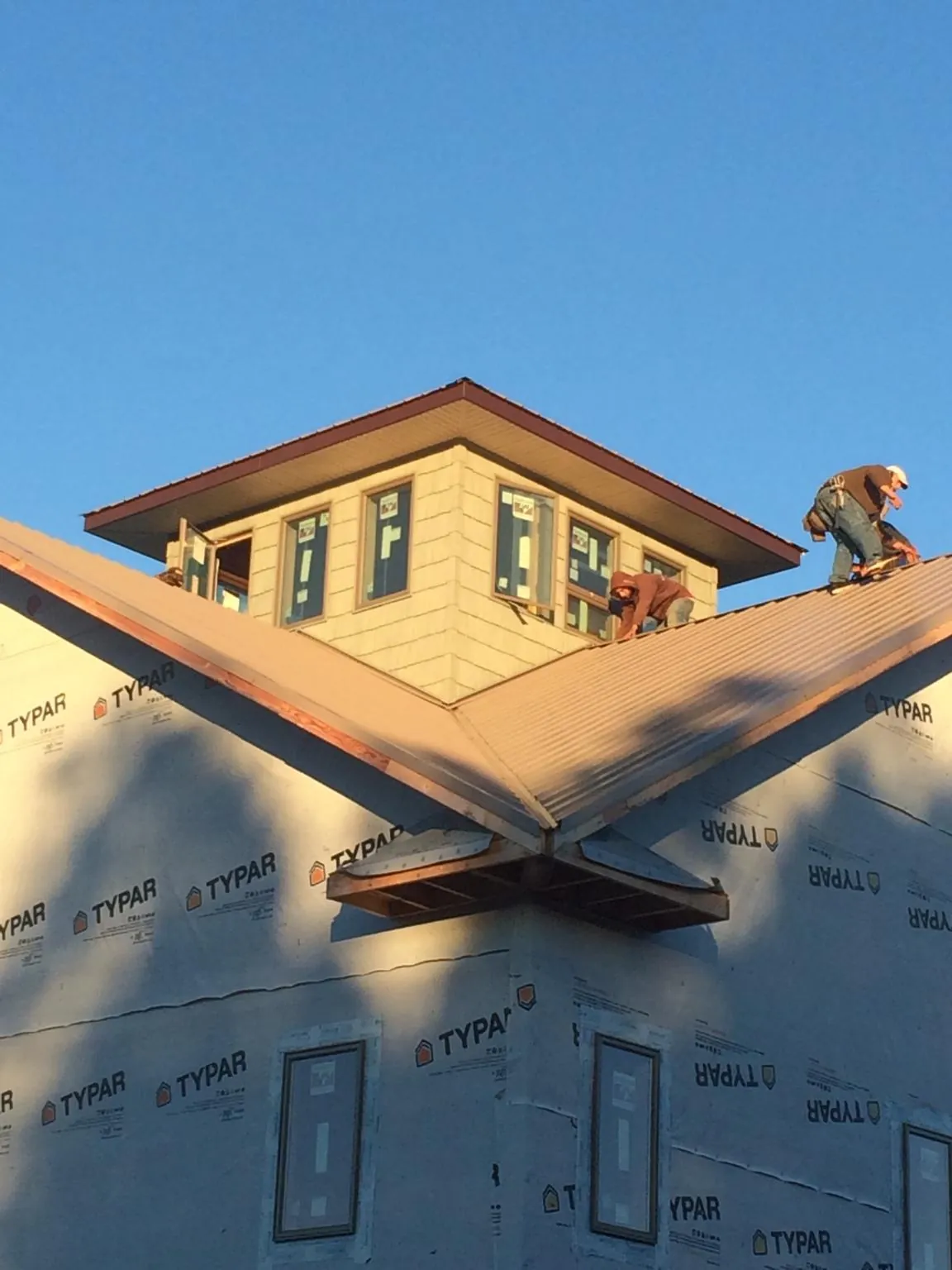 Roofers working around a rooftop cupola on a new metal roof at sunset — Roof Waterproofing in Kennedy by Roofing Brothers